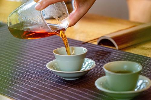 a person pouring tea into cups on a table at Wuyu Sky Garden Hotel Chongqing Zoo & Yangjiaping The Mixc Light rail in Chongqing