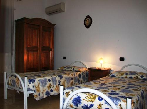 a bedroom with two beds and a wooden cabinet at B&B La Piccola Oasi in Lazzaro
