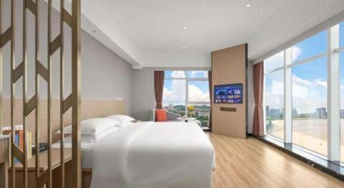 a bedroom with a large white bed and a television at Grand Nest Hotel (Tang Jia Wan Beach) in Zhuhai