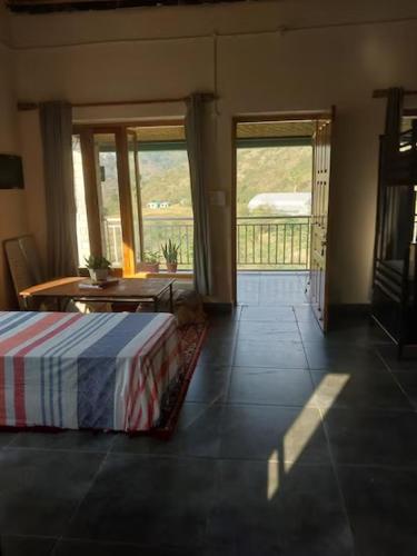 a bedroom with a bed and a door to a balcony at Himkosi Farm by the River in Almora
