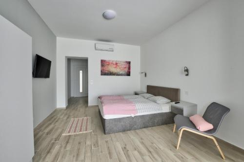 um quarto com uma cama, uma televisão e uma cadeira em Villa Oliver 2 Siófok em Siófok