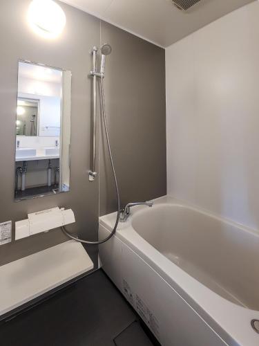 a bathroom with a bath tub and a mirror at 豆の家Beanz House in Niseko