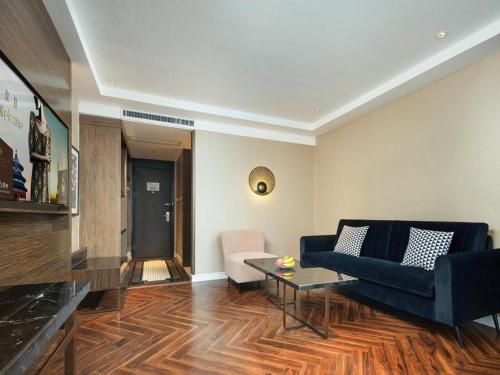 a living room with a blue couch and a table at Jinjiang Metropolo Hotel - Taizhou Wanda Plaza in Taizhou