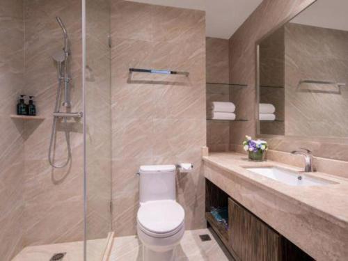 a bathroom with a shower and a toilet and a sink at Landmark Hotel in Zhuhai