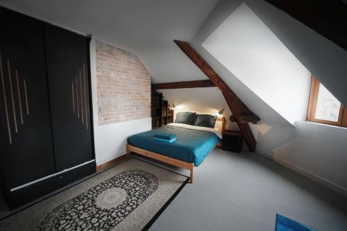 une chambre avec un lit bleu dans un grenier dans l'établissement T4 hyper centre d' Angers, à Angers