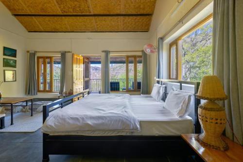 a bedroom with a large bed with a large window at Himkosi Farm by the River in Almora