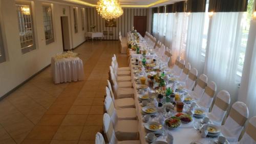 a long table with white tables and chairs in a room at Hotel Gościniec in Włocławek