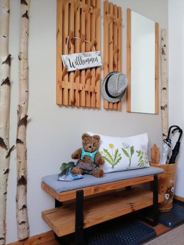 a teddy bear sitting on a bench in a room at Die KALSBERGERin Ferienwohnung für Genießer in Donnersbachwald