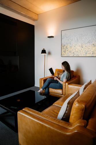 a woman sitting on a couch with a laptop at Hotel Verge Launceston in Launceston