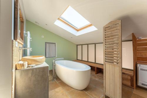 ein Badezimmer mit großer Badewanne und Oberlicht in der Unterkunft Ferme La Clavière, Maison de vacances Lou Mas in Mane