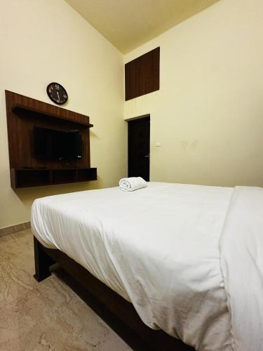 a bedroom with a bed and a clock on the wall at Deep Rich Farm villa Munnar in Anachal