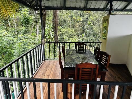 a table and chairs on a deck with a view of the forest at Deep Rich Farm villa Munnar in Anachal