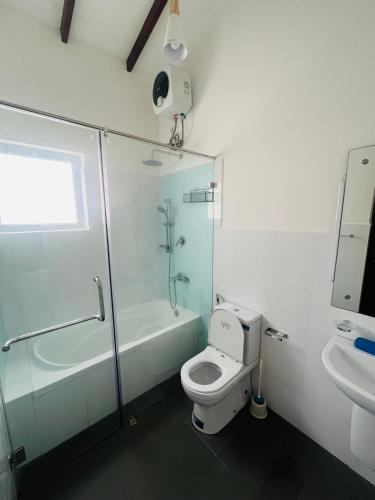 a bathroom with a toilet and a shower and a sink at Celestial Negombo Resort Villa 10 in Negombo