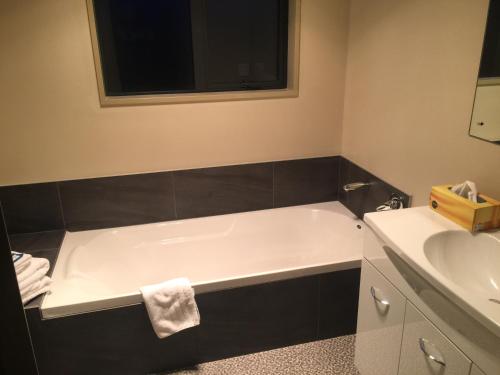 ein Badezimmer mit einer Badewanne und einem Waschbecken in der Unterkunft Lawrence Townhouse Accommodation 18A in Lawrence