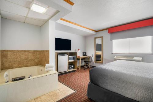 a hotel room with a bed and a desk and a television at Super 8 by Wyndham Eveleth in Eveleth