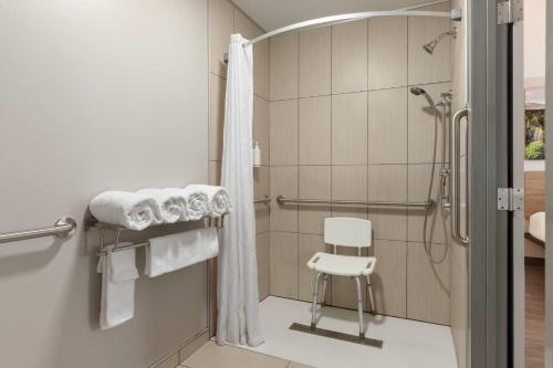 a bathroom with a shower and a white chair at Days Inn by Wyndham Worland in Worland