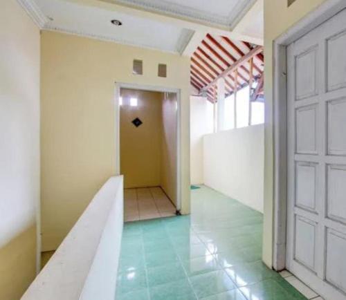 a room with a door and a hallway with green floors at GRIYA HARMONI Homestay Jogja in Adi Sutjipto