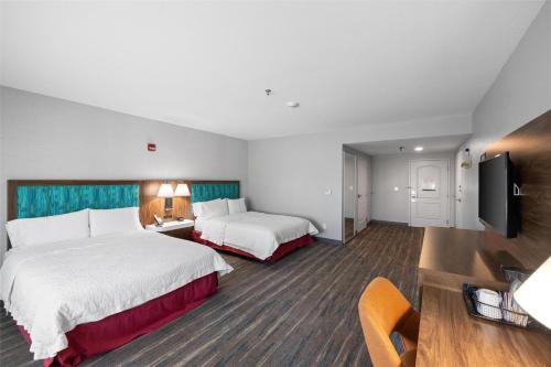a hotel room with two beds and a flat screen tv at Hampton Inn & Suites Madera in Madera