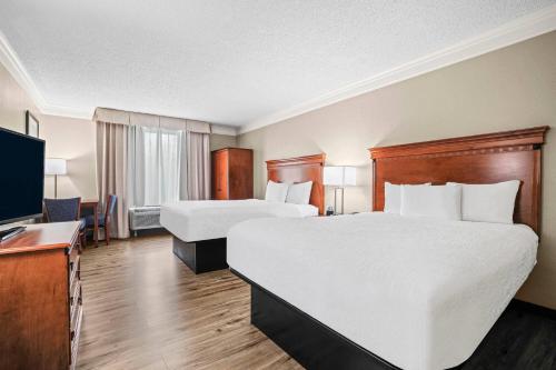 a hotel room with two beds and a flat screen tv at Baymont by Wyndham Madisonville in Madisonville