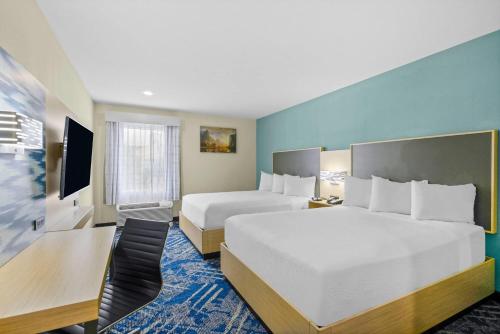 a hotel room with two beds and a desk at Baymont by Wyndham Grovetown Augusta in Augusta