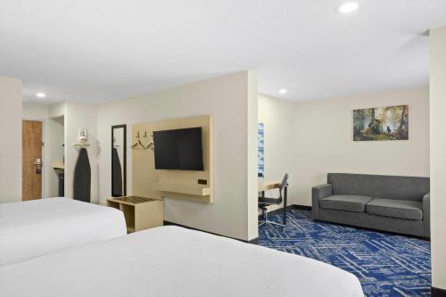 a hotel room with a bed and a couch at Baymont by Wyndham Grovetown Augusta in Augusta
