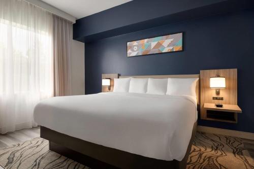 a large white bed in a room with a blue wall at La Quinta by Wyndham Montgomery in Montgomery