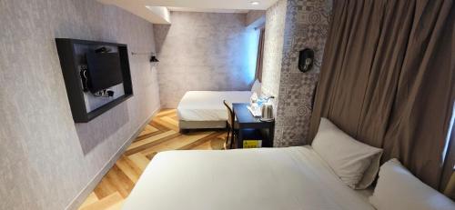 a small room with two beds and a tv at 慶爾喜旅館西門捷運館Gugis Inn in Taipei