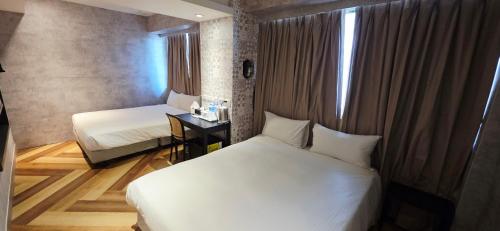 a bedroom with two beds and a desk and a window at 慶爾喜旅館西門捷運館Gugis Inn in Taipei
