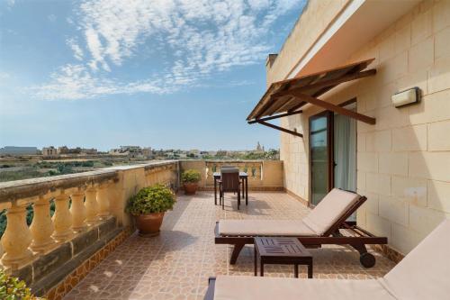 a balcony of a house with a chair and a table at Kempinski Hotel San Lawrenz in San Lawrenz