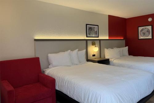 a hotel room with two beds and a red chair at Travelodge by Wyndham Lumberton in Lumberton