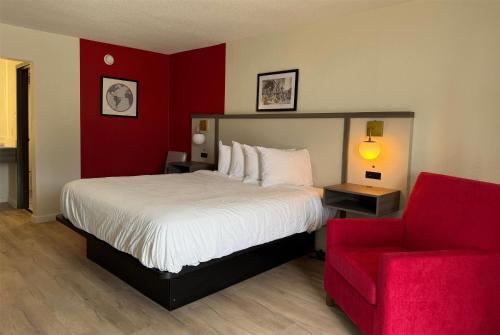 a bedroom with a large bed and a red wall at Travelodge by Wyndham Lumberton in Lumberton