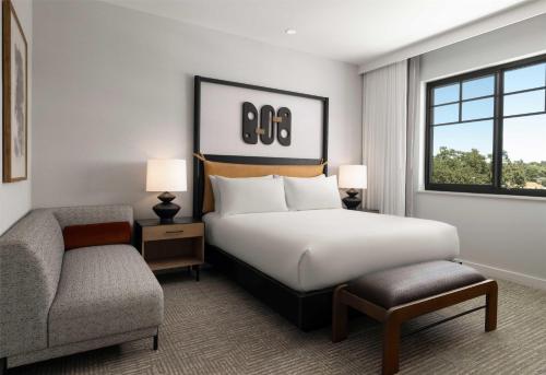 a bedroom with a bed and a chair and a window at The Ava Hotel Paso Robles, Curio Collection By Hilton in Paso Robles