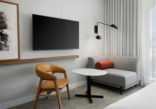 a living room with a chair and a table and a tv at The Ava Hotel Paso Robles, Curio Collection By Hilton in Paso Robles
