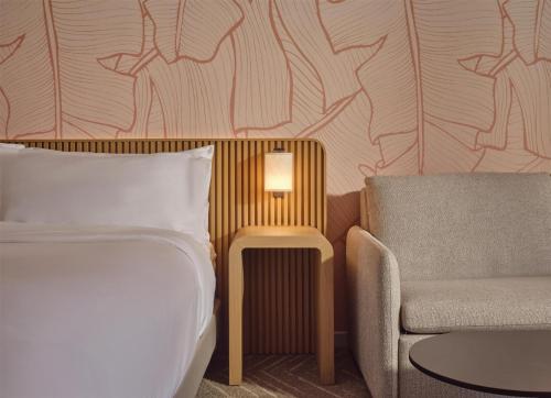 a bedroom with a bed and a couch and a chair at The Ambassador of Waikiki, Tapestry Collection by Hilton in Honolulu