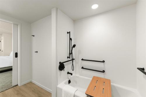 a white bathroom with a bathtub and a wooden table at The Ambassador of Waikiki, Tapestry Collection by Hilton in Honolulu