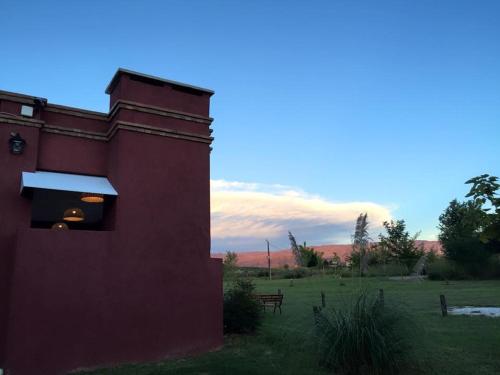 a red building with a bench in a field at Casonas de Nono in Nono