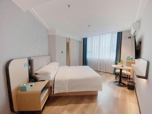 a hotel room with a bed and a table and a desk at City Comfort Inn Nanning Guangxi University in Nanning