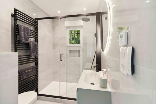 a white bathroom with a shower and a sink at Villa L'Emeraude in Cavalaire-sur-Mer