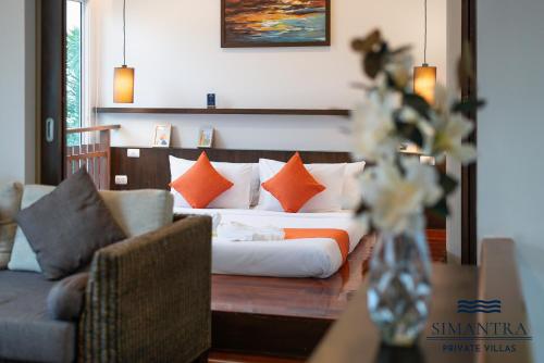 a bedroom with a couch and a bed with orange pillows at Simantra Private Villas in Cha Am