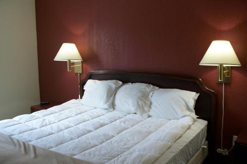 a bed in a bedroom with two lamps on the wall at Budget Inn & Suites in Wall Township