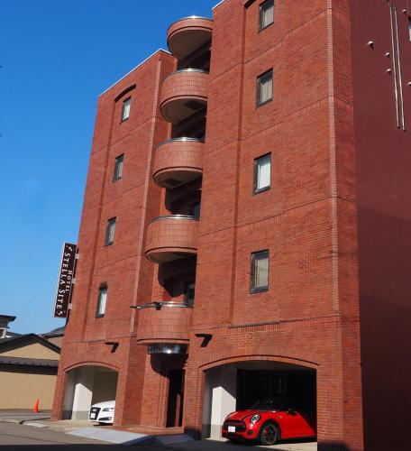 a red car parked in front of a red brick building at ステラサイト函館 in Hakodate
