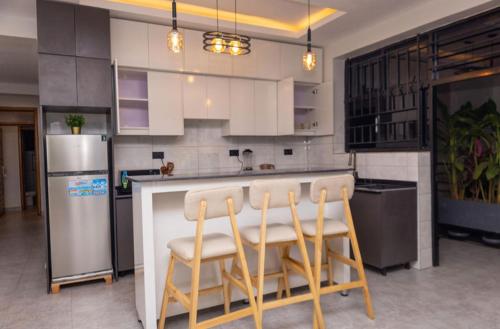 a kitchen with a counter with chairs and a refrigerator at Serene Apartments in Kigali