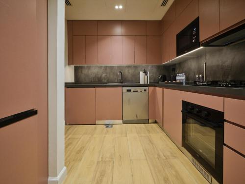 a large kitchen with wooden floors and pink cabinets at The Muse in Doha