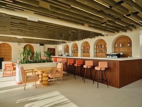 a lobby with a bar with orange chairs and tables at The Muse in Doha