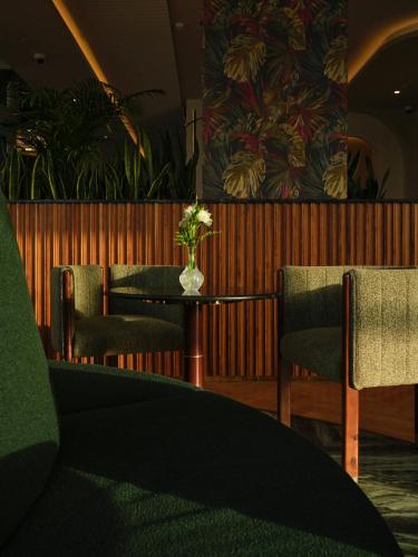 a table and chairs with a vase of flowers on it at The Muse in Doha
