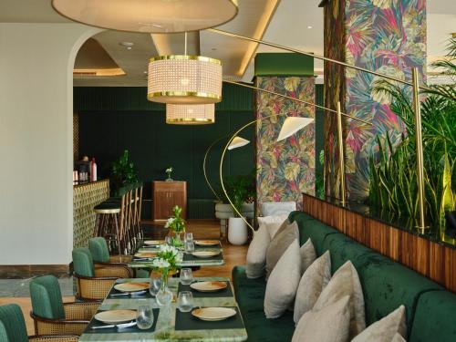 a dining room with a green couch and tables at The Muse in Doha