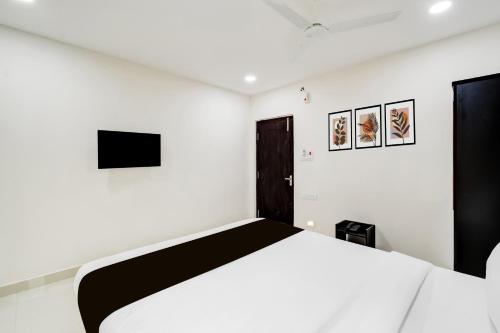 a white bedroom with a bed and a tv at Super Townhouse Golden Temple Manikonda in Gachibowli