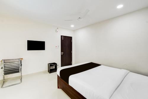 a white bedroom with a bed and a tv at Super Townhouse Golden Temple Manikonda in Gachibowli