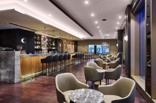 a bar in a restaurant with chairs and tables at Parmelia Hilton Perth in Perth