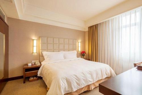 a bedroom with a large white bed and a window at Best Western Plus Fuzhou Fortune Hotel in Fuzhou